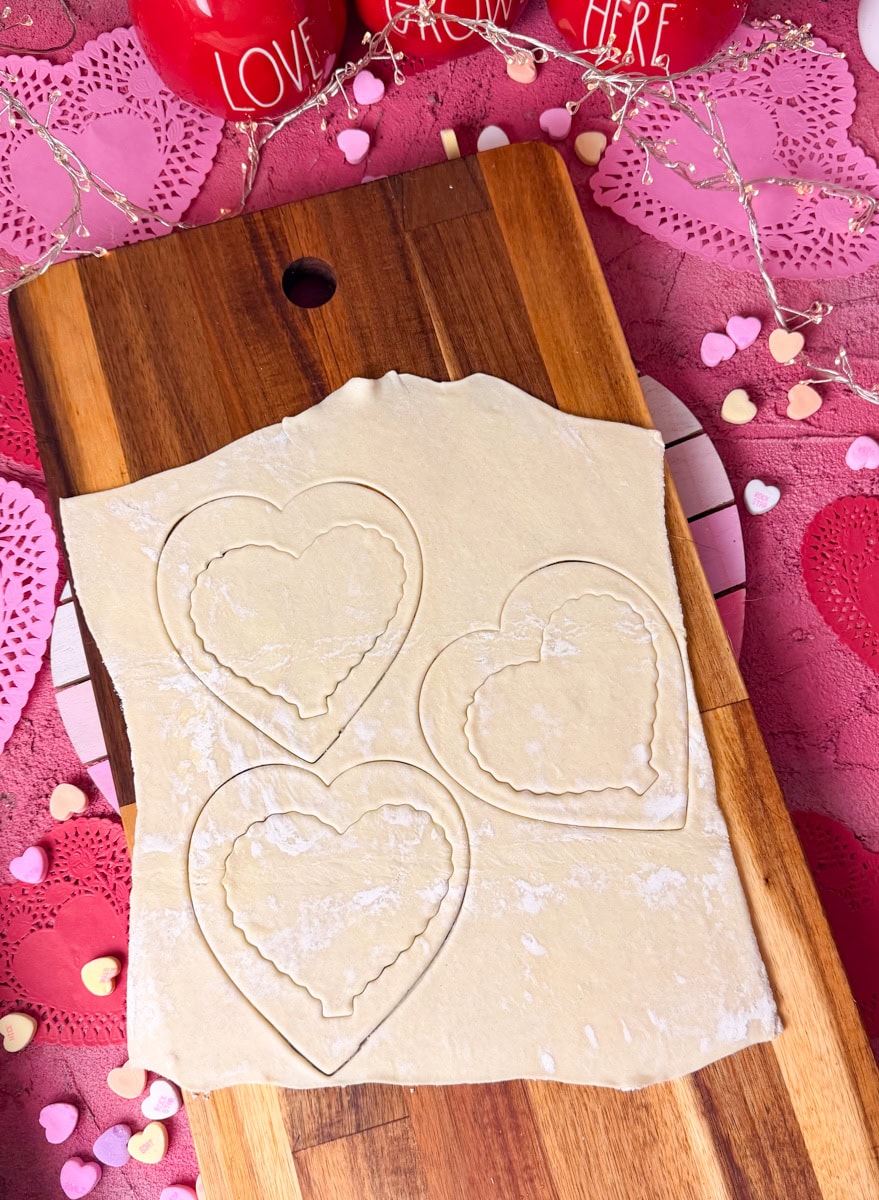 Heart shapes cut from puff pastry with smaller heart indent in center for strawberry cream cheese danish hearts.