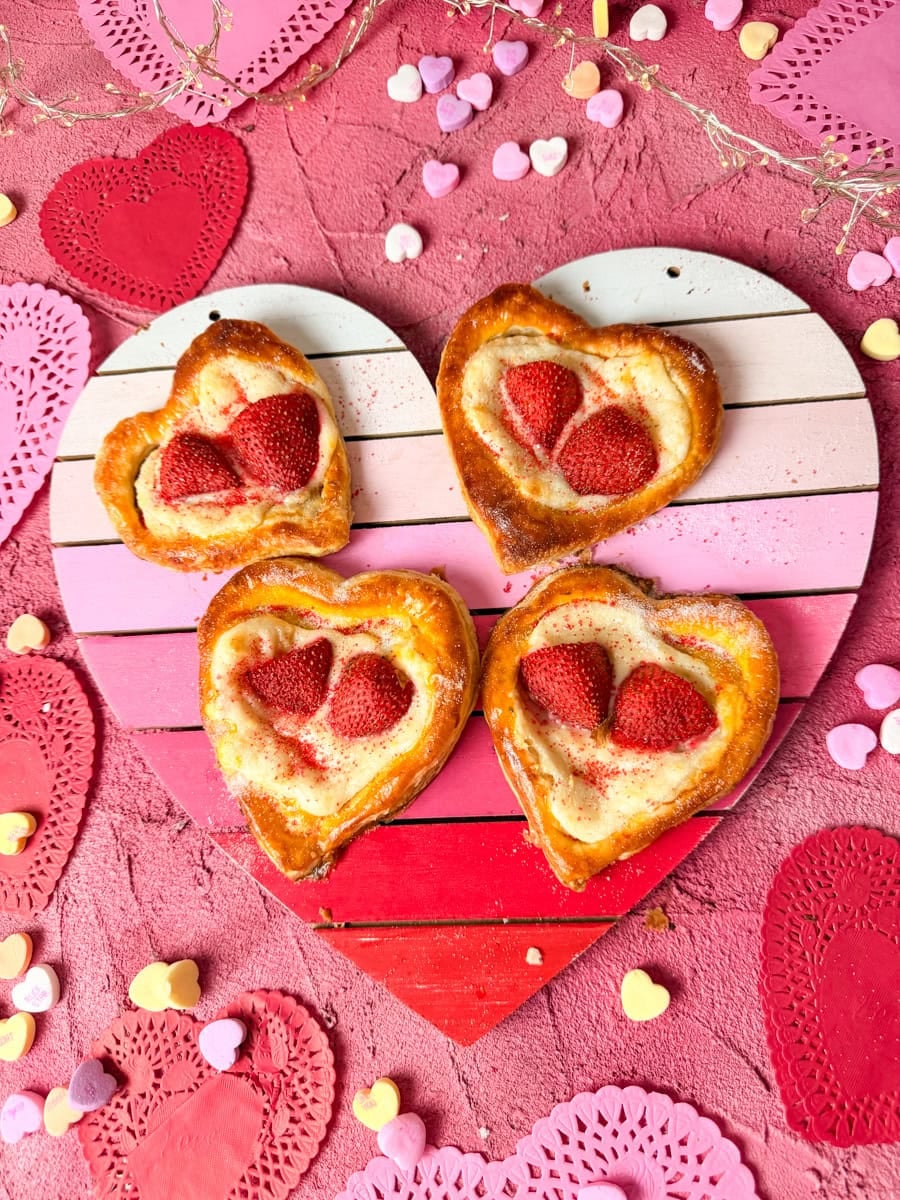 strawberry cream cheese danishes on a heart wooden back drop with candy conversation hearts