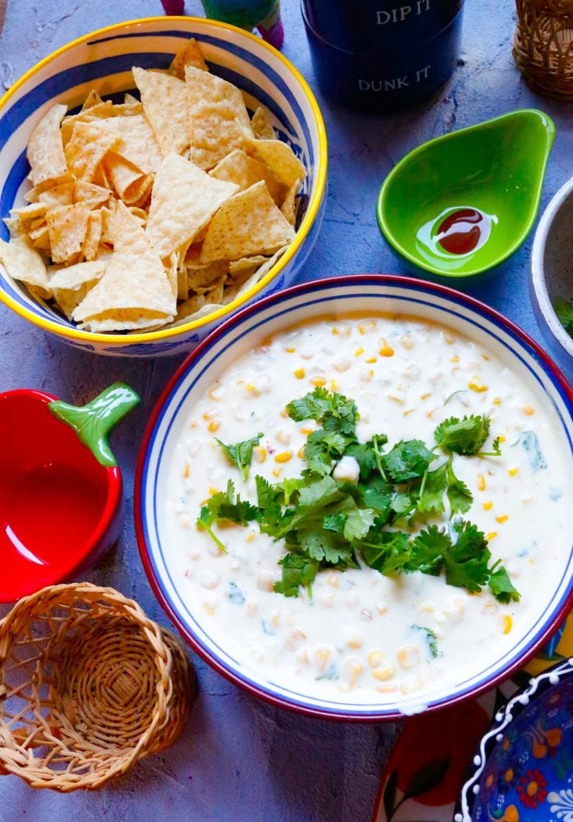 Creamy Mexican street corn dip in a bowl topped with fresh cilantro, served with tortilla chips