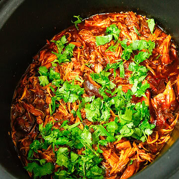 Shredded slow cooker BBQ chicken finished with fresh cilantro in the crockpot, saucy and tender