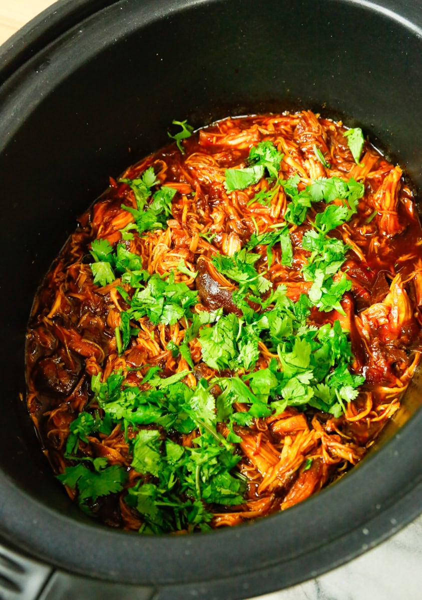 Shredded slow cooker BBQ chicken finished with fresh cilantro in the crockpot, saucy and tender