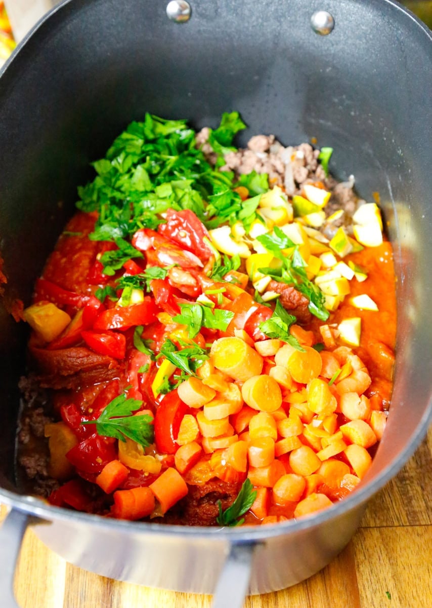 Carrots, diced tomatoes, garlic, and fresh herbs added to slow cooker ravioli soup
