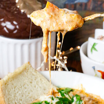Easy creamy slow cooker ravioli soup with ground beef, spinach, and cheese ravioli in a rich tomato broth with a melty cheese pull.