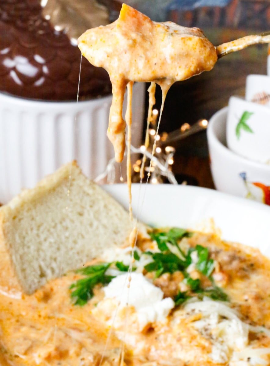 Easy creamy slow cooker ravioli soup with ground beef, spinach, and cheese ravioli in a rich tomato broth with a melty cheese pull.