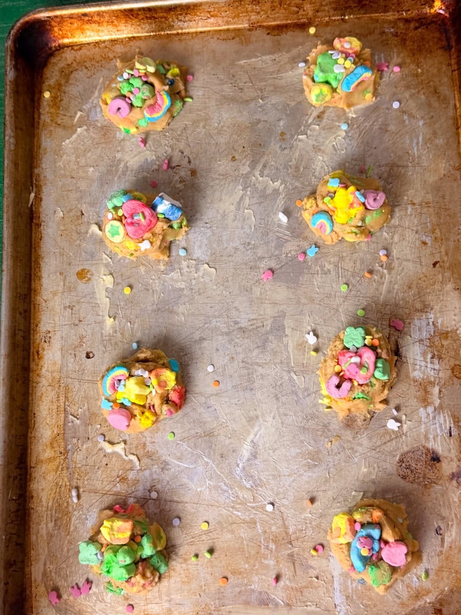 Scoops of Lucky Charms cookie dough placed on a baking sheet before baking
