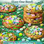 Colorful Lucky Charms cookies topped with marshmallow cereal pieces and sprinkles on a green background with rainbow text reading “Lucky Charms Cookies Recipe (Easy One-Bowl)” and Fitty Foodlicious branding.