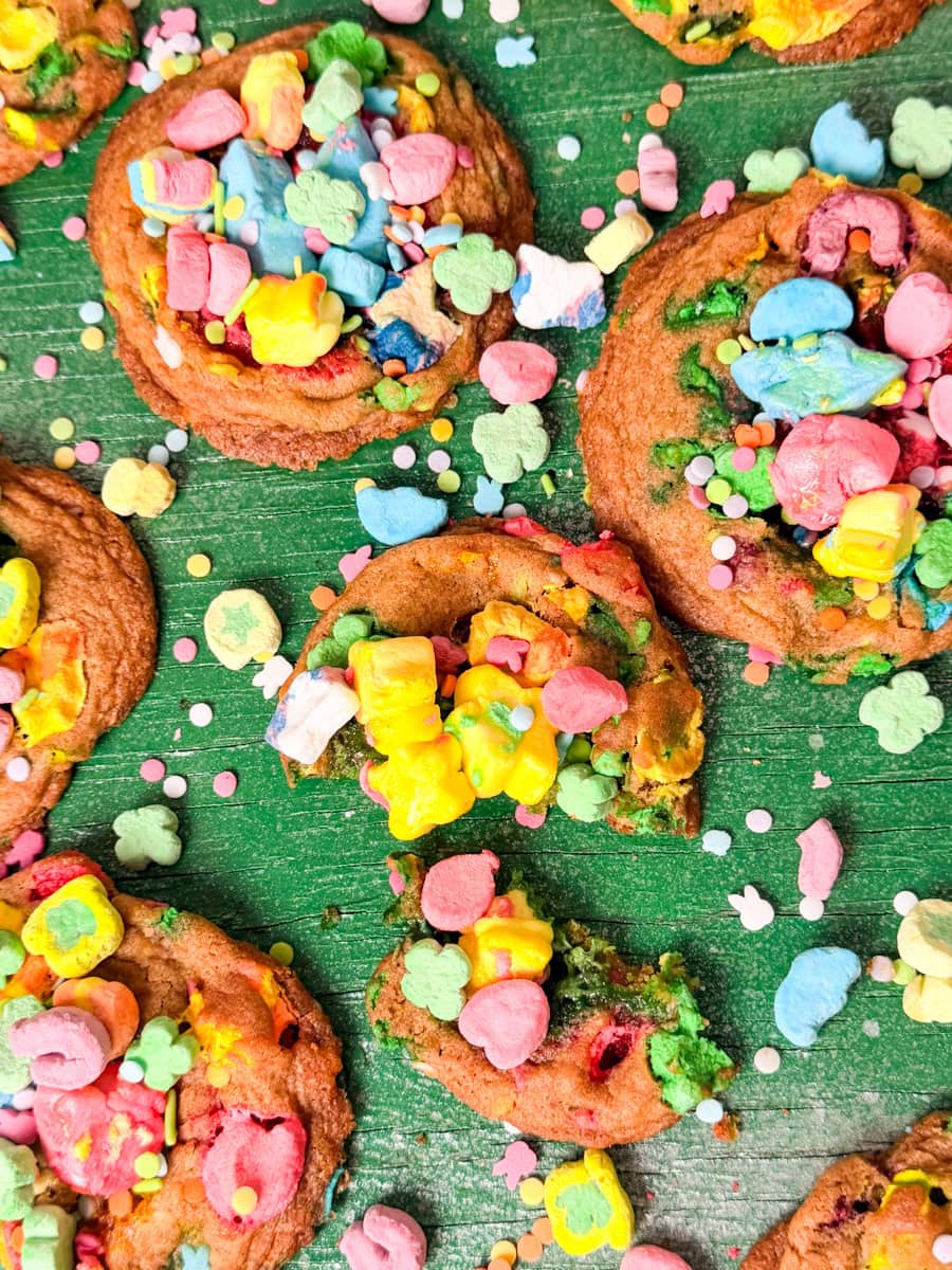 Soft baked Lucky Charms cookies topped with colorful marshmallow cereal pieces and sprinkles on a green background