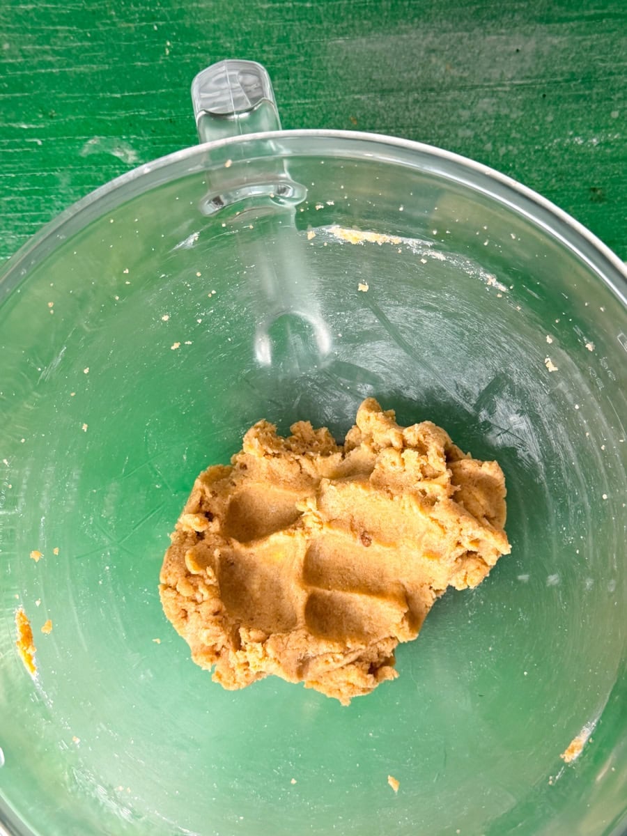 Butter, white sugar, and brown sugar being mixed together with egg in a bowl