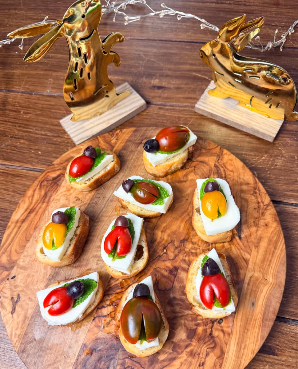 adding kalamata olive pieces as ladybug heads on cherry tomato crostini appetizer