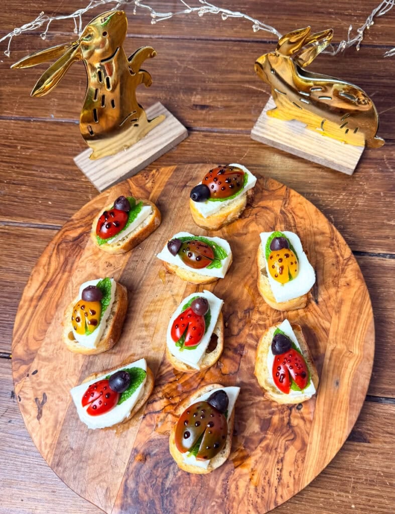 ladybug crostini appetizer with cherry tomatoes mozzarella and basil arranged on wooden serving board