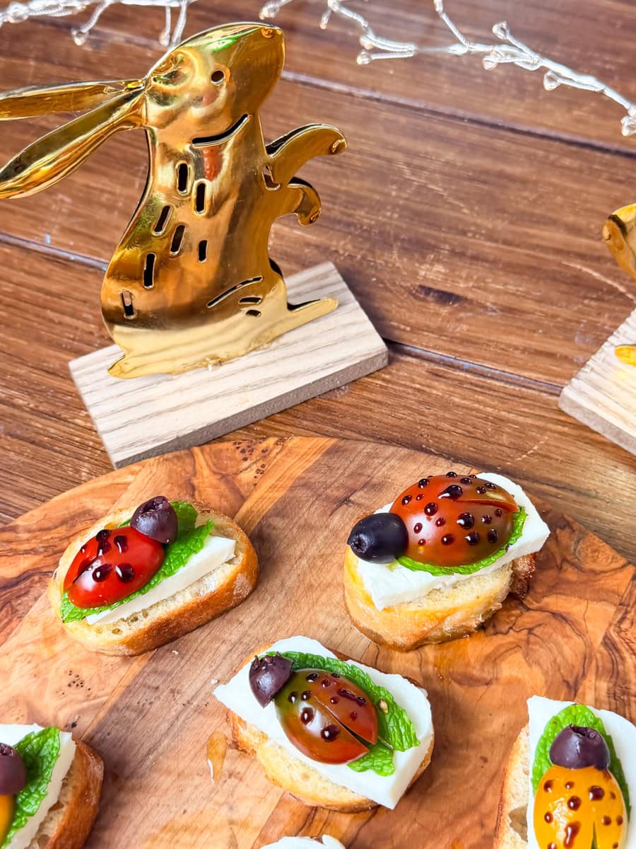 close up of ladybug crostini appetizer with cherry tomatoes mozzarella basil leaves and balsamic glaze on toasted bread