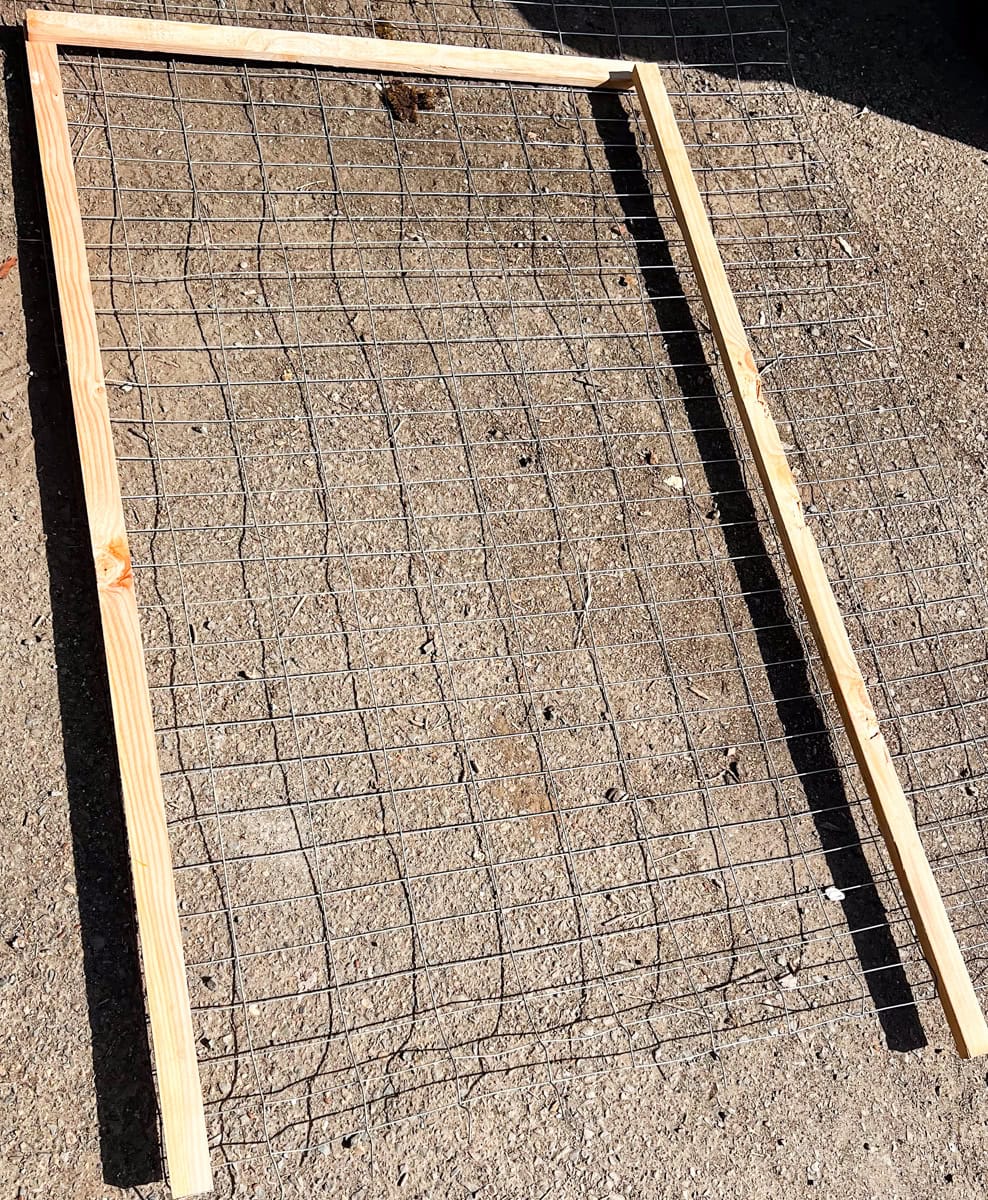 wooden trellis frame pieces laid out with hog wire panel during DIY garden trellis build