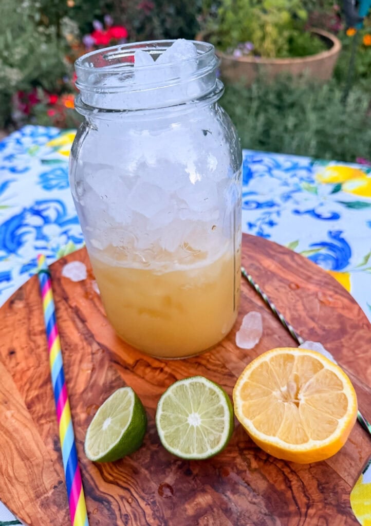 Ice added to a mason jar filled with healthy homemade lemon lime soda mixture made with fresh lemon juice, lime juice, maple syrup, and Baja sea salt before adding sparkling water.