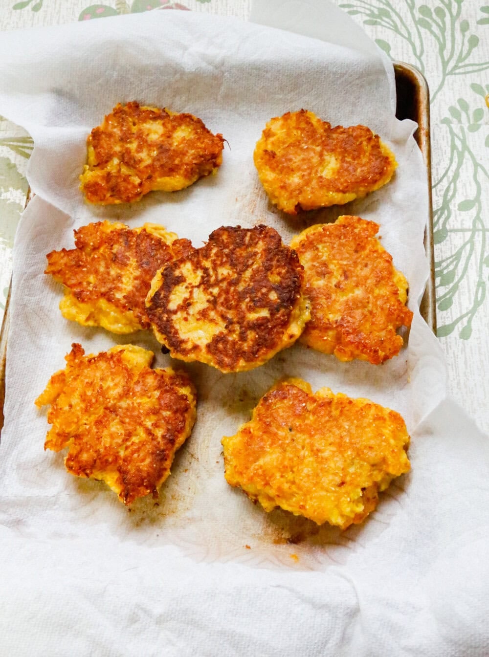 Crispy golden brown squash fritters resting on paper towels after frying.