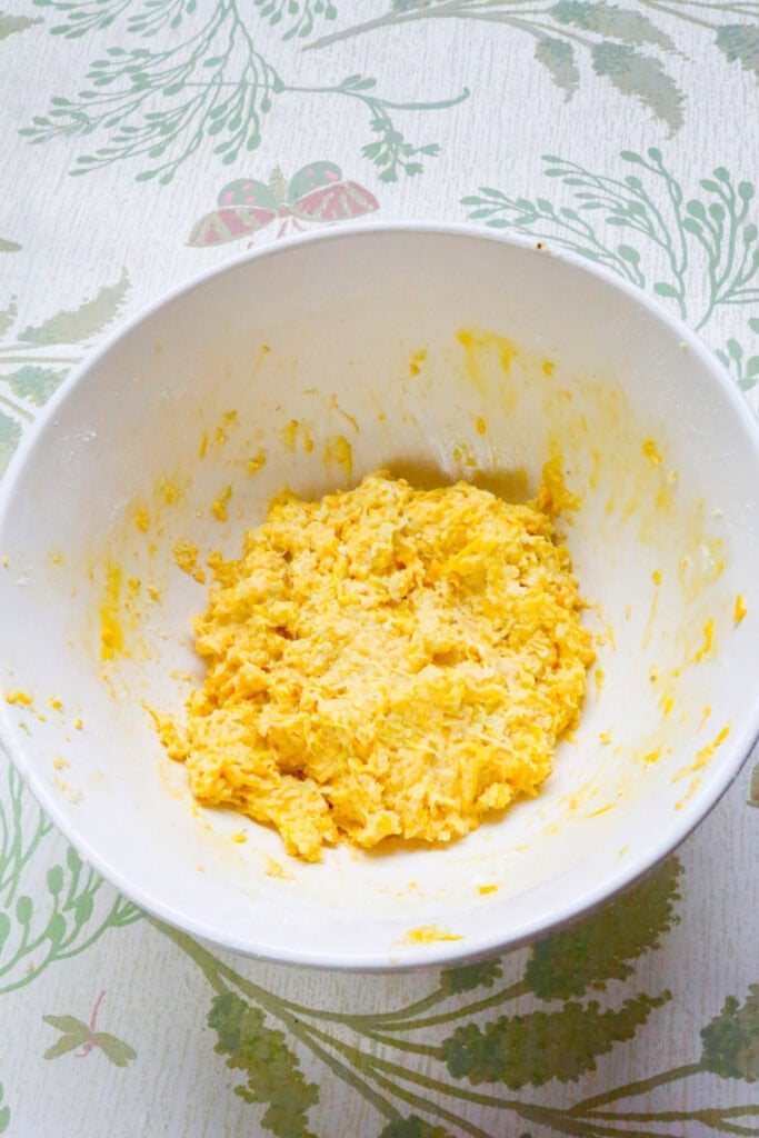 Mixed yellow squash fritter batter in a white bowl before forming into patties.