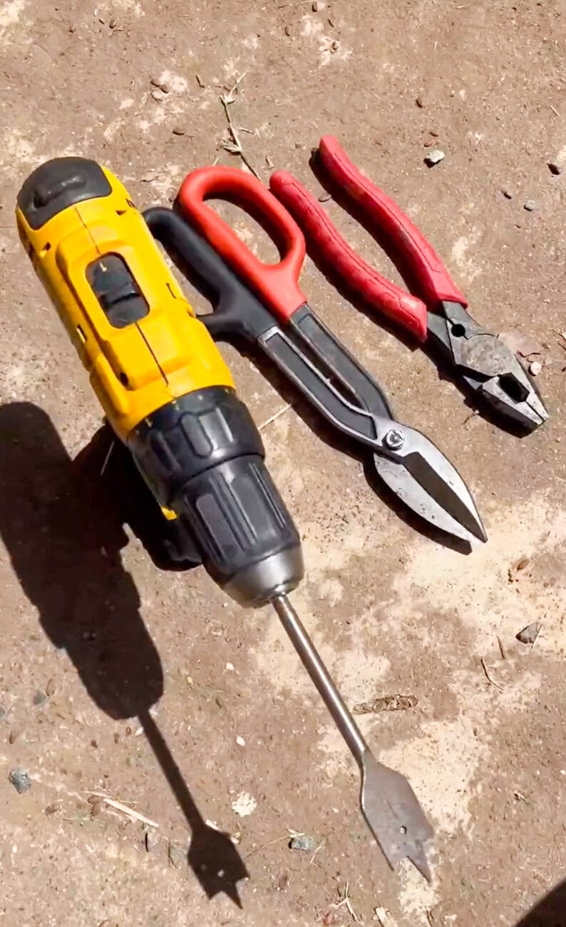 Cordless drill, drill bit, and hand tools used to create a DIY outdoor hose and extension cord storage bucket tutorial.