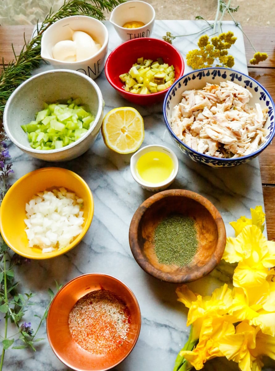 Ingredients for dill pickle chicken salad with rotisserie chicken, celery, dill pickles, onion, mayonnaise, lemon juice, and seasonings.