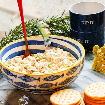 Dill pickle chicken salad made with rotisserie chicken, celery, and dill pickles served in a fish-pattern bowl with crackers.