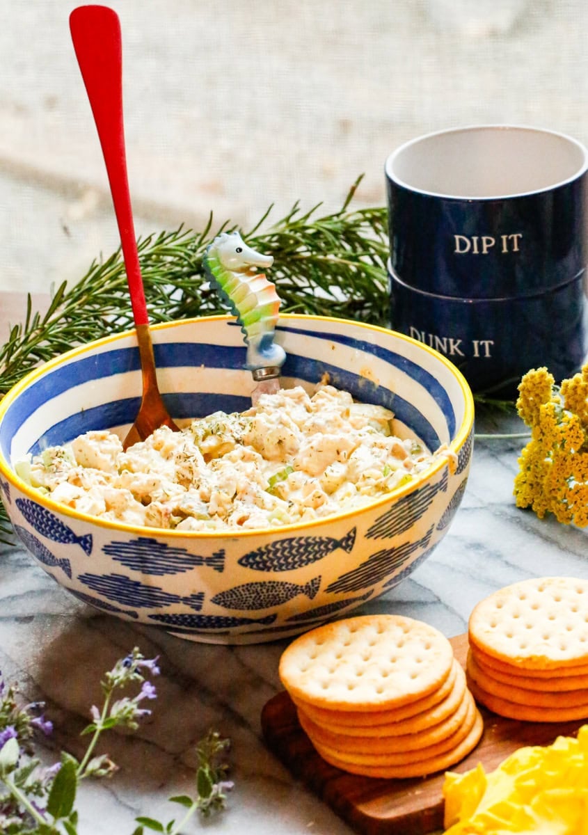 Dill pickle chicken salad made with rotisserie chicken, celery, and dill pickles served in a fish-pattern bowl with crackers.