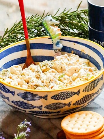 Creamy chicken salad made with rotisserie chicken, chopped pickles, celery, and a tangy dressing served with crackers in a bowl.