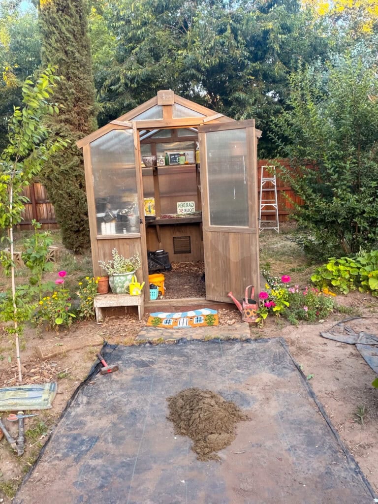 Preparing the ground for a garden path by laying weed barrier fabric before adding leveling sand and stepping stone pavers.