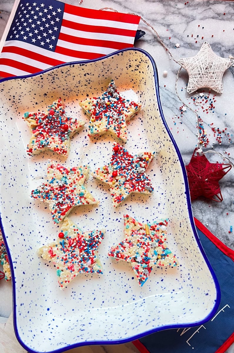 Star-shaped Fourth of July Rice Krispie treats decorated with red, white, and blue sprinkles on a serving platter.