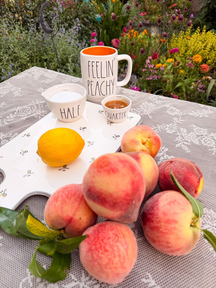 Fresh peaches, honey, sugar, and a lemon on a table before making peach jam.
