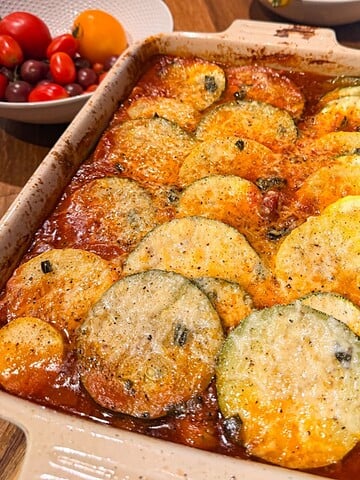 Freshly baked ratatouille with roasted zucchini, yellow squash, tomatoes, and sage in a casserole dish after baking.