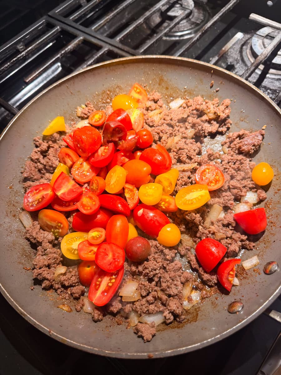 Fresh cherry and heirloom tomatoes added to a skillet with browned ground beef and onions to make homemade ratatouille sauce.