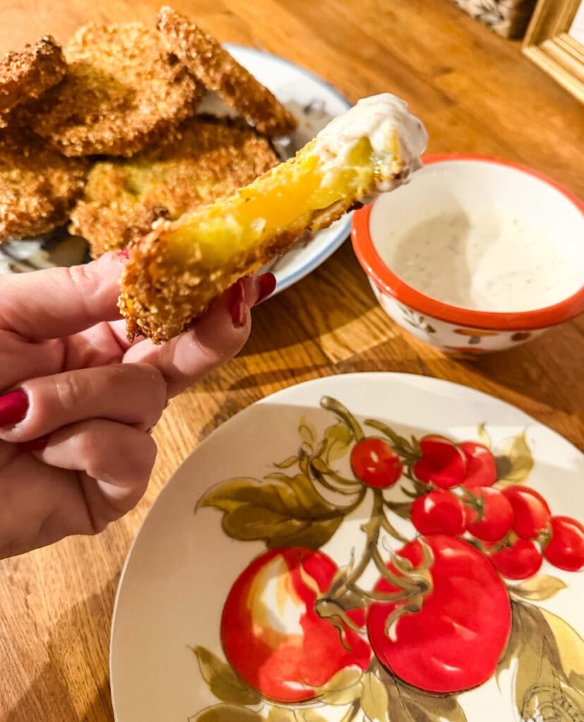 Fried green tomato with a bite taken out showing the tender green tomato center and crispy cornmeal coating.