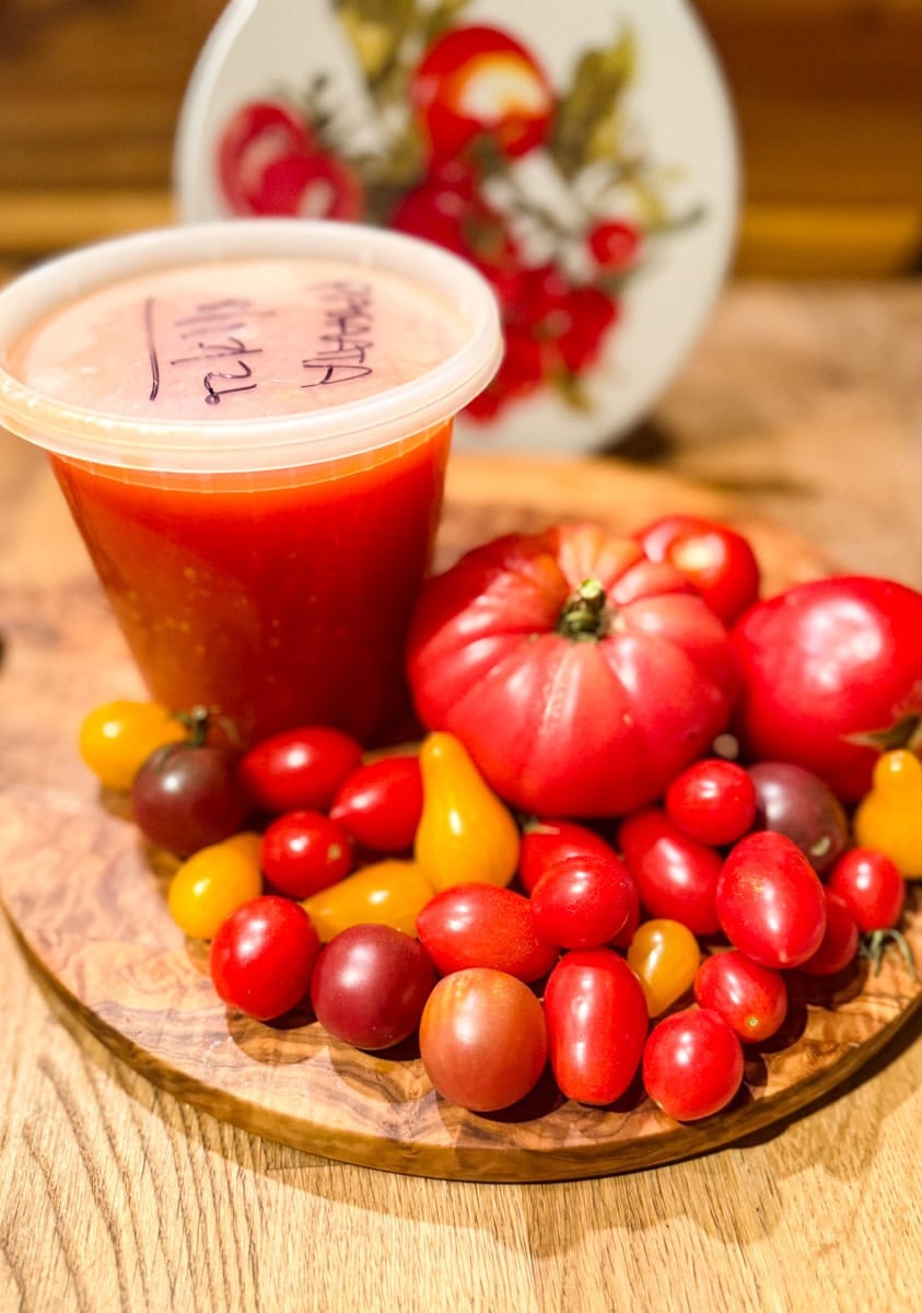 Bowl of fresh garden tomatoes beside a container of Homemade Tomato Passata.