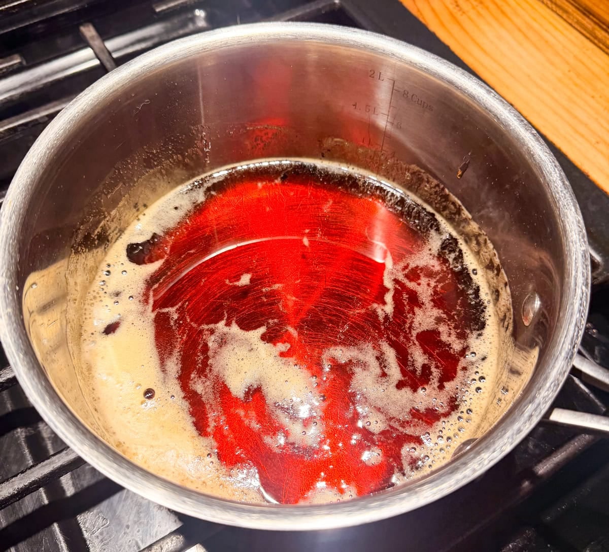 Pure maple syrup heating in a saucepan on the stovetop for Homemade Maple Butter.