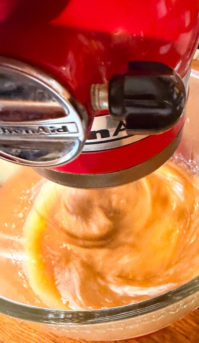 Cooked maple syrup mixing in a stand mixer to make Homemade Maple Butter.