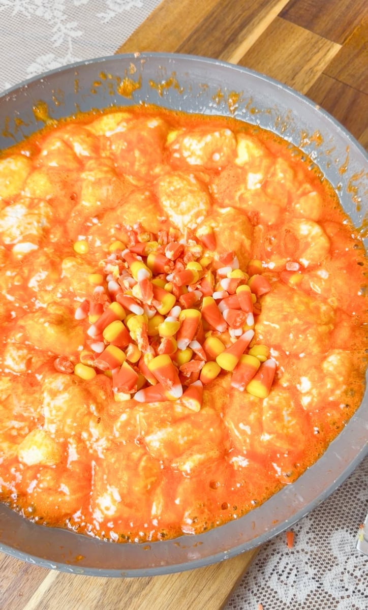 Jumbo marshmallows, candy corn marshmallows, and chopped candy corn melting with butter in a saucepan until smooth, gooey, and lava-like for Halloween Rice Krispies Treats.