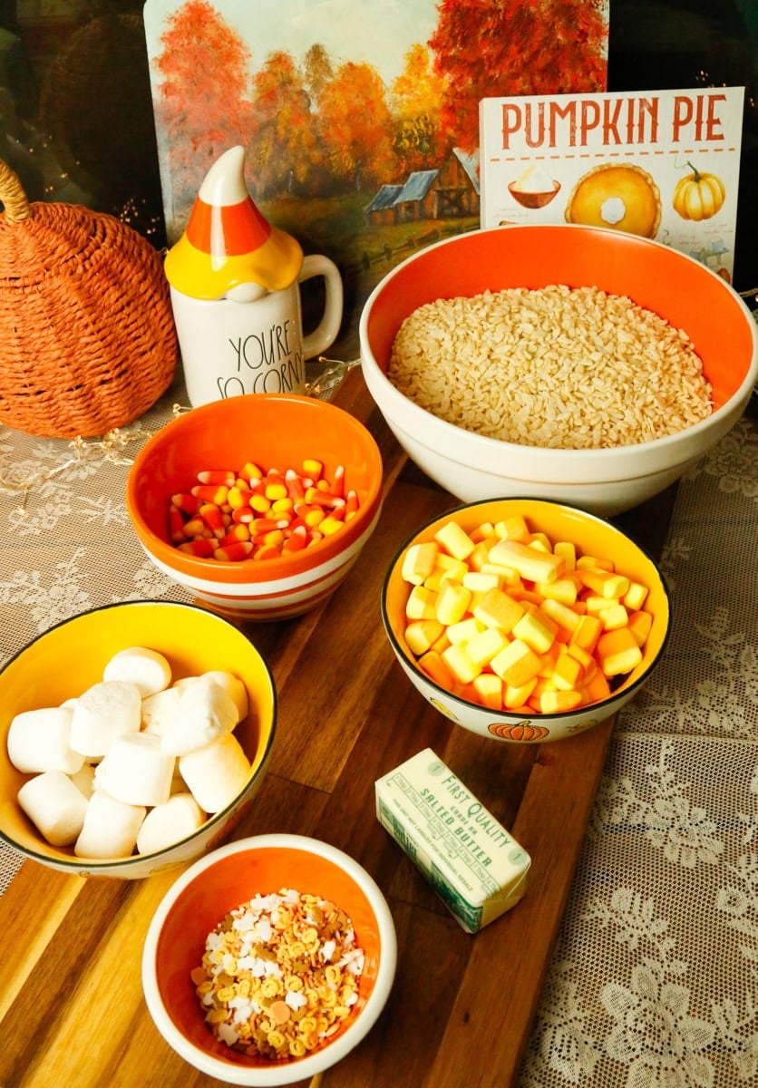 Ingredients for Halloween Rice Krispies Treats, including crispy rice cereal, candy corn marshmallows, jumbo marshmallows, butter, candy corn, and Halloween sprinkles.