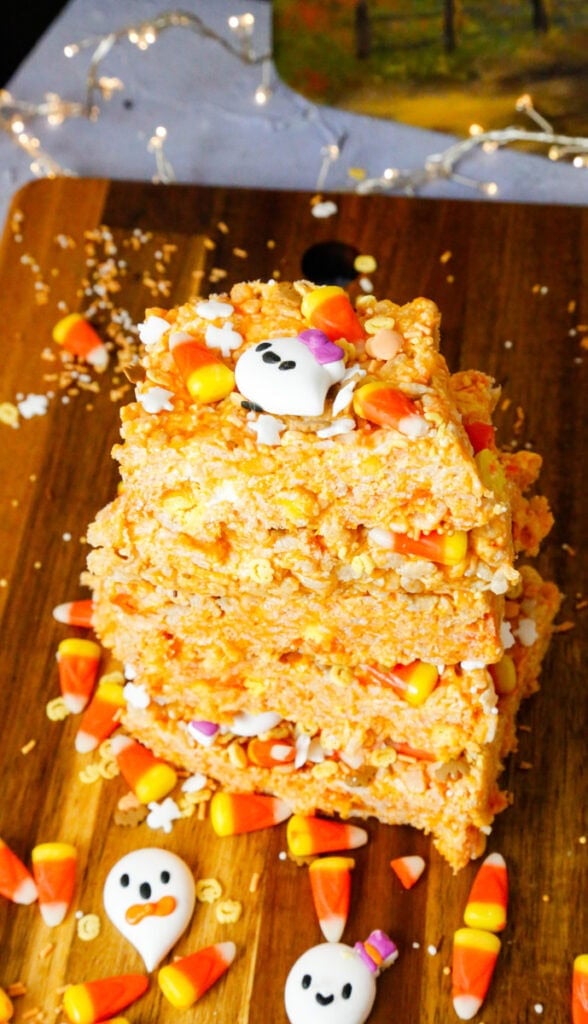 Stacked Halloween Rice Krispies Treats decorated with colorful candy corn and cute ghost candies on a festive Halloween serving tray.
