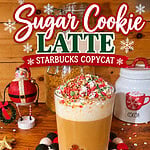 Pinterest graphic featuring a homemade Starbucks copycat Sugar Cookie Latte topped with whipped cream and Christmas sprinkles in a gingerbread glass, surrounded by festive Santa decorations, with the recipe website FittyFoodlicious.com.